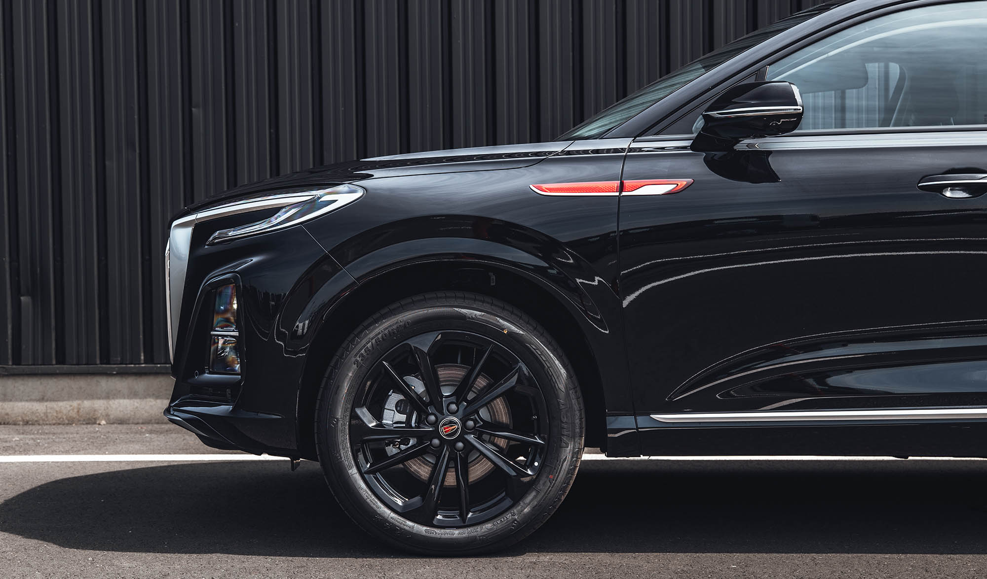 Close-up side view of a black Hongqi HS3 showing the front wheel and exterior design details